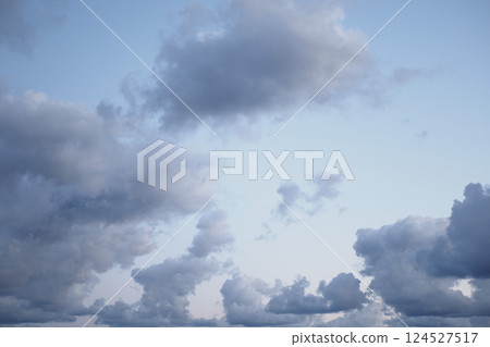 Soft gray clouds drift across a serene blue sky at dusk 124527517