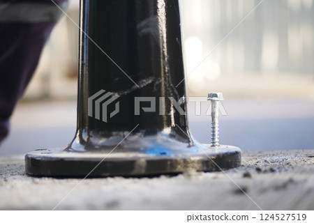 Fixing a pole base on a city street during daylight hours 124527519