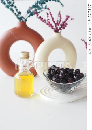 Olive oil and black olives on a table with vases and decor 124527547