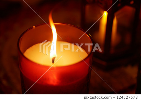 Candle flame glows softly in cozy indoor setting at night Candle flame glows softly in cozy indoor setting at night 124527578