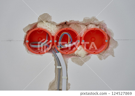 Electrical wiring installation with exposed wires and wall sockets during renovation 124527869