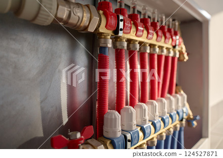 Underfloor heating system manifold with red pipes and control valves Underfloor heating system manifold with red pipes and control valves 124527871