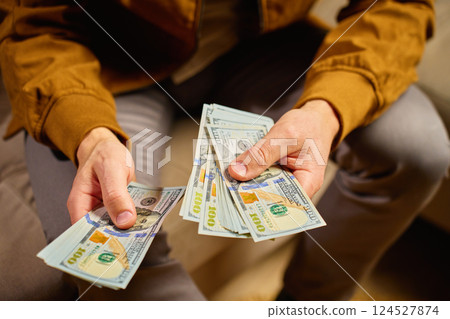 Man managing personal finances at home, counting dollar banknotes 124527874