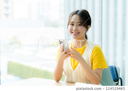 A student looking at a smartphone in a cafe 124529465
