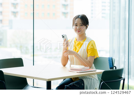 A student looking at a smartphone in a cafe A student looking at a smartphone in a cafe 124529467