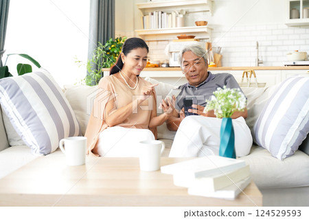 Asia happy senior elderly couple trading stock for investment after retirement at living room. 124529593