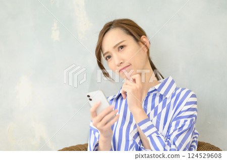 A woman looking at her smartphone and worrying 124529608