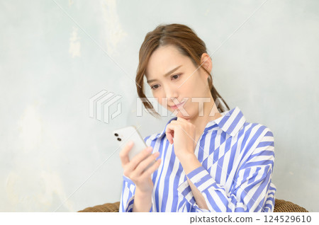 A woman looking at her smartphone and worrying A woman looking at her smartphone and worrying 124529610