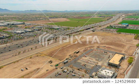 Aerial view shows busy highway near fields, construction, showcasing urban growth in desert near Phoenix Arizona Aerial view shows busy highway near fields, construction, showcasing urban growth in desert near Phoenix Arizona 124529680