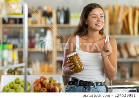 Young woman choosing olives in grocery store Young woman choosing olives in grocery store 124529981