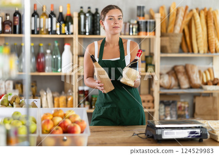 Young female seller offering wine in grocery store Young female seller offering wine in grocery store 124529983