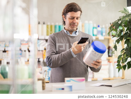 Man in pharmacy scans QR code on infant formula product 124530248
