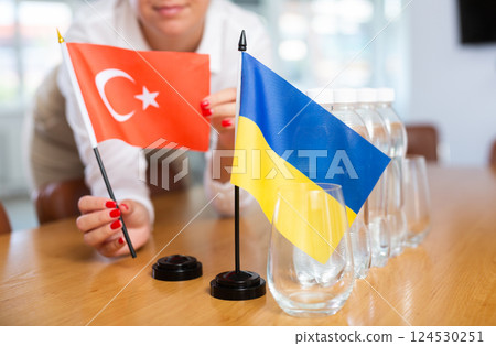 Unrecognizable girl sets midget flags of Ukraine and Turkey before international negotiations 124530251