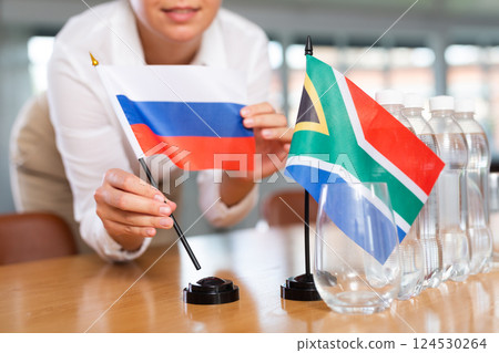 Blurry girl set midget flags of South Africa and Russia before international negotiations 124530264