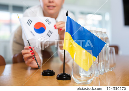 Unrecognizable girl sets midget flags of Ukraine and South Korea before international negotiations Unrecognizable girl sets midget flags of Ukraine and South Korea before international negotiations 124530270