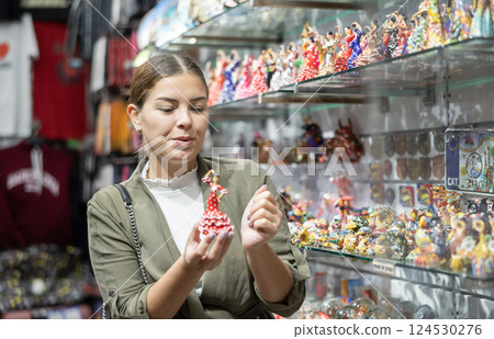 Curious female tourist looking to buy pretty ceramic dancer figurines at souvenir shop 124530276