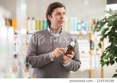 Man choose antitussive syrup in pharmacy 124530286