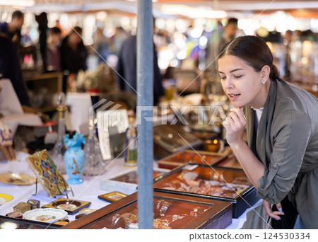 Portrait of smiling young woman choosing vintage goods at flea market 124530334