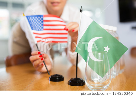 Young woman puts flags of USA and Pakistan on table in office Young woman puts flags of USA and Pakistan on table in office 124530340