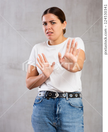 Irritated young woman posing crossly against gray background Irritated young woman posing crossly against gray background 124530341