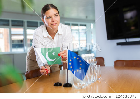 Young woman puts flags of Pakistan and EU on table in office Young woman puts flags of Pakistan and EU on table in office 124530373