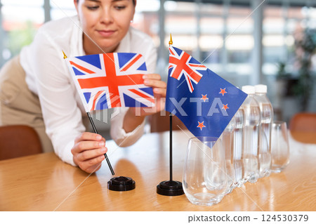 Preparing for business presentation - secretary places flags of Great Britain and Australia on negotiating table Preparing for business presentation - secretary places flags of Great Britain and Australia on negotiating table 124530379