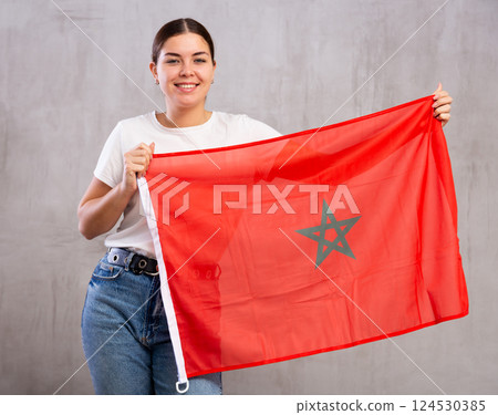 Happy female fan of favorite team of Morocco with the national flag in her hands Happy female fan of favorite team of Morocco with the national flag in her hands 124530385