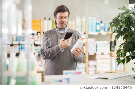 Man in pharmacy scans QR code on emollient cream product 124530446