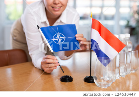 Blurry girl set midget flags of Netherlands and NATO before international negotiations Blurry girl set midget flags of Netherlands and NATO before international negotiations 124530447