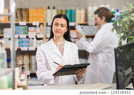 Female pharmacist taking inventory with tablet Female pharmacist taking inventory with tablet 124530451