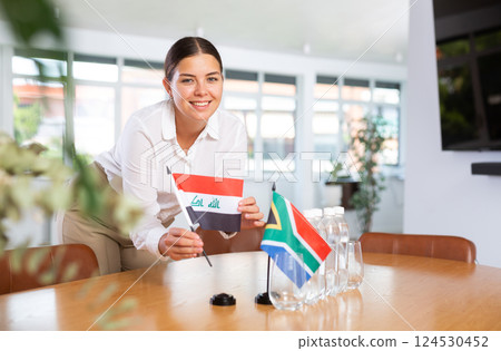 Young lady sets miniatures flags of South Africa and Iraq for international negotiations Young lady sets miniatures flags of South Africa and Iraq for international negotiations 124530452