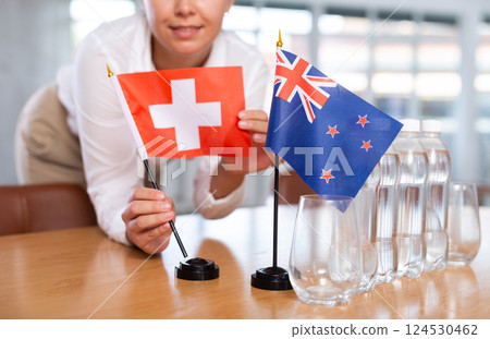 Female secretary places flags of the Australia and Switzerland flag on the table before negotiations of top political figures 124530462