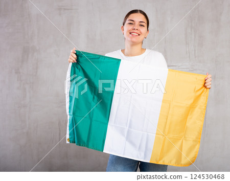 Happy girl stands with flag of Ireland. Isolated on gray background Happy girl stands with flag of Ireland. Isolated on gray background 124530468