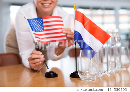 Preparing for negotiations - female employee of the protocol department places flags of the USA and Netherlands 124530503
