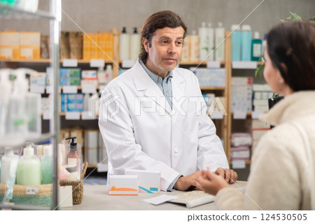 Pharmacist searches for medicine on computer for female buyer 124530505