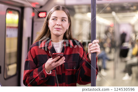 woman stands in the subway and holds on to a handrail 124530596