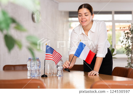 Female secretary places flags of the USA and France on the table before negotiations of top political figures 124530597