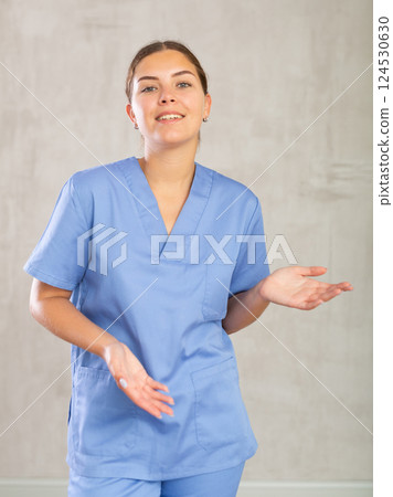 Young happy female nurse showing somewhere with her hands Young happy female nurse showing somewhere with her hands 124530630