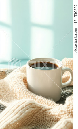 cozy coffee cup on soft knit blanket in warm sunlight 124530852