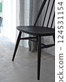 A black chair on a bare concrete floor 124531154
