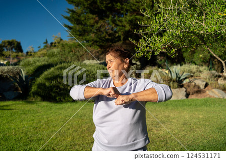 Elderly woman exercising in park on sunny day Elderly woman exercising in park on sunny day 124531171