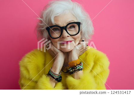 An elderly woman with a charming smile and vibrant fashion. Portrait on a pink background 124531417