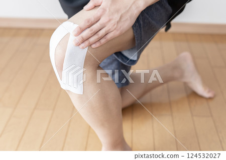 Man applying a compress to his knee, knee pain, sprain, joint pain, body parts Man applying a compress to his knee, knee pain, sprain, joint pain, body parts 124532027