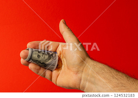 Dollar bill held in hand against a red background Dollar bill held in hand against a red background 124532183