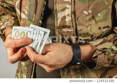 Soldier holding cash in military uniform indoors Soldier holding cash in military uniform indoors 124532188