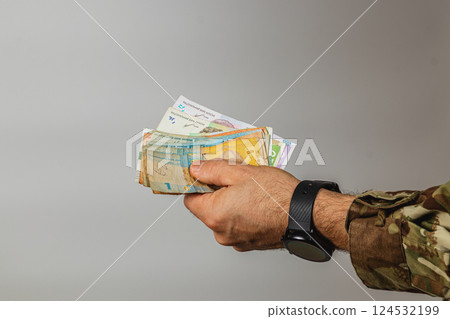 Hand holding various banknotes in a neutral setting Hand holding various banknotes in a neutral setting 124532199