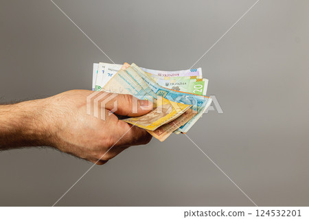 Hand holding various banknotes against a neutral background Hand holding various banknotes against a neutral background 124532201