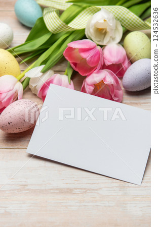 Easter greeting card lying near colorful eggs and pink tulips on white wooden table Easter greeting card lying near colorful eggs and pink tulips on white wooden table 124532636