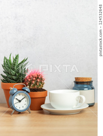 Coffee cup, alarm clock and cacti creating relaxing morning atmosphere on desk Coffee cup, alarm clock and cacti creating relaxing morning atmosphere on desk 124532648