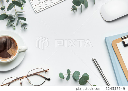 Eucalyptus branches, coffee, keyboard, and mouse framing white desk background Eucalyptus branches, coffee, keyboard, and mouse framing white desk background 124532649